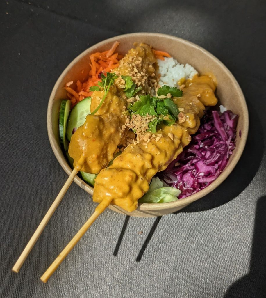 Bol de riz, brochettes de poulet sauce cacahuète et crudités